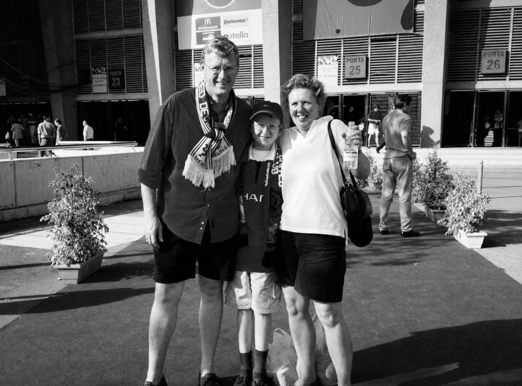 Man, child and woman in front of stadium