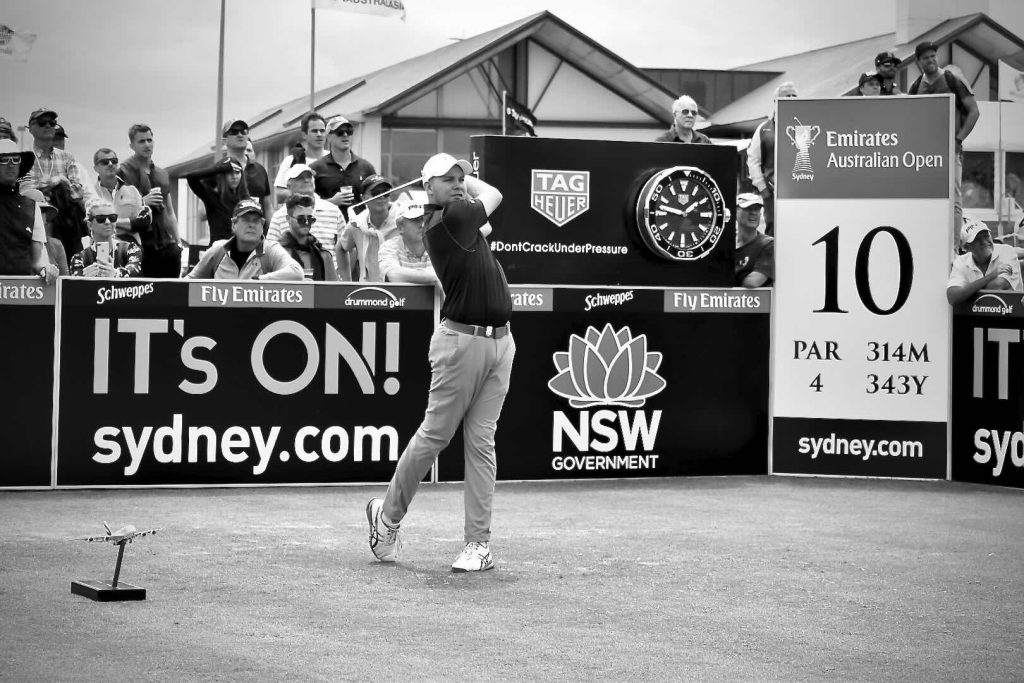 A young golfer teeing off the 10th hole in front of of a gallery
