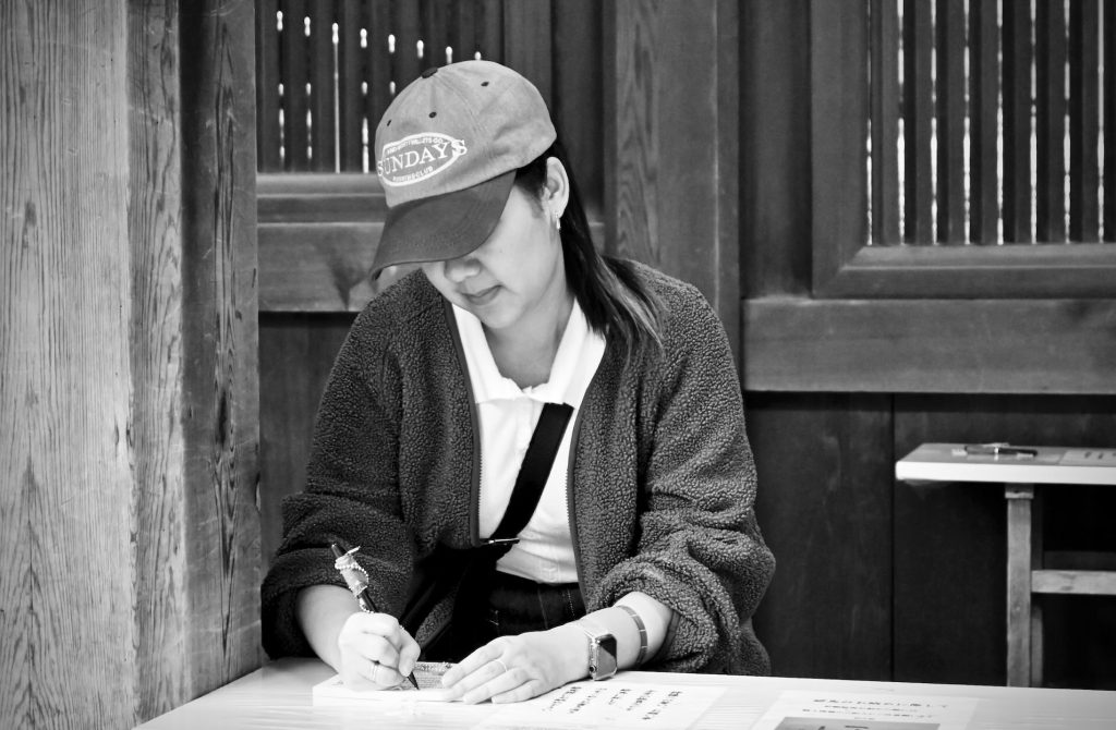A woman with a baseball cap, writing a note