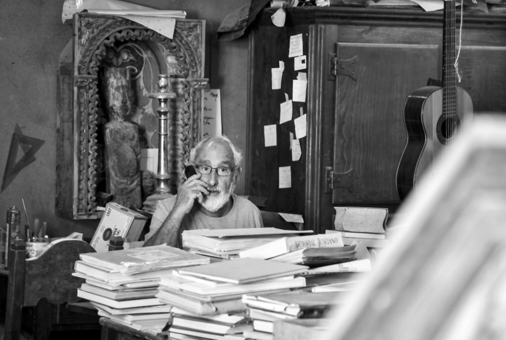 A man sat behind lots of books on a desk